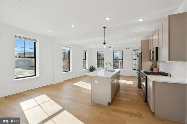 a large kitchen with kitchen island a large counter top space a sink stainless steel appliances and cabinets