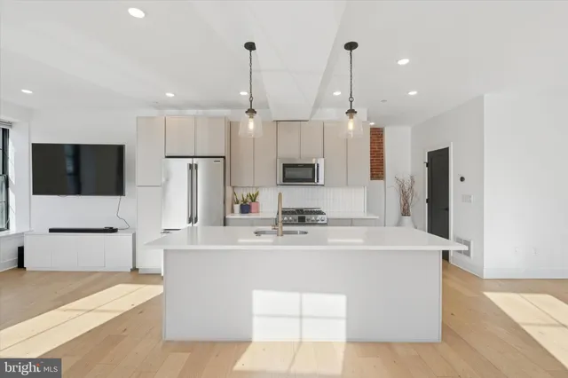 a kitchen with stainless steel appliances kitchen island granite countertop a sink a stove and a refrigerator
