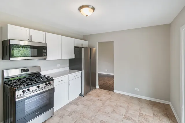 a kitchen with stainless steel appliances a stove a microwave and white cabinets