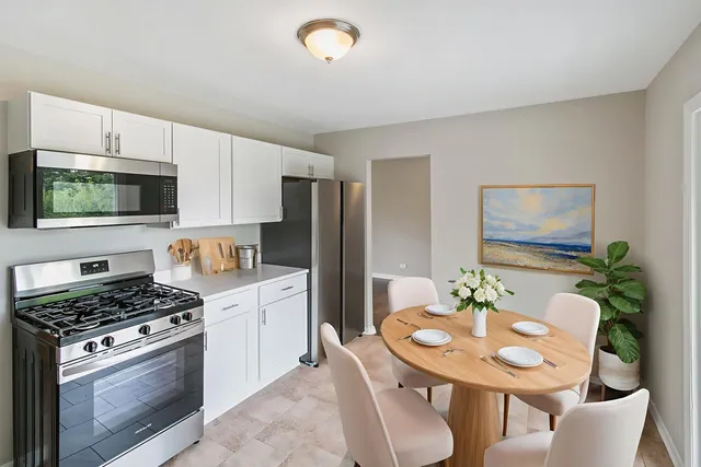 a kitchen with stainless steel appliances kitchen island granite countertop a sink a stove a refrigerator with a dining table and chairs