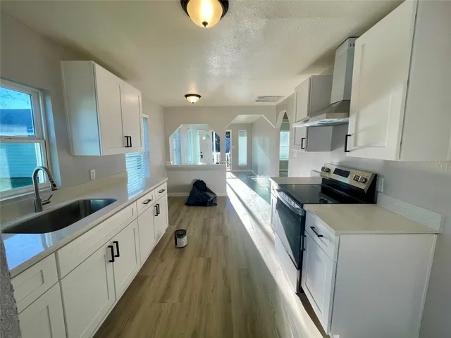 a kitchen with counter top space a sink wooden floor and cabinets