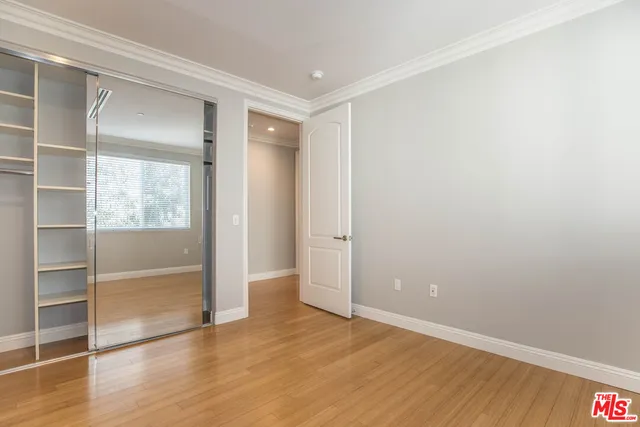 a view of an empty room with wooden floor and closet