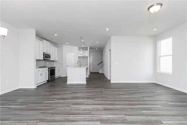 a view of kitchen and kitchen with sink wooden floor oven and cabinets