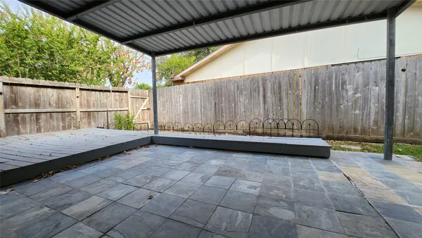a view of a backyard with large trees and wooden fence