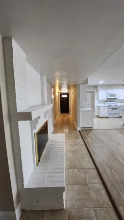 an empty room with wooden floor and kitchen view