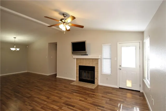 a view of a livingroom with a fireplace a ceiling fan and wooden floor