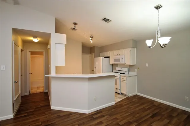 a kitchen with stainless steel appliances a refrigerator a sink dishwasher a stove and white cabinets with wooden floor