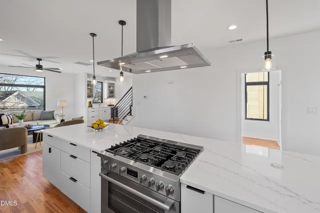 a kitchen with stainless steel appliances a stove a sink a refrigerator and white cabinets with wooden floor