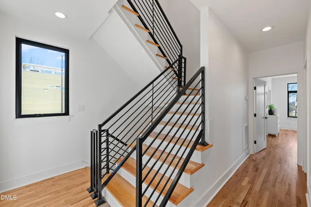 a view of an empty room with window and wooden floor