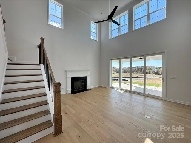 a view of an empty room with wooden floor and a fireplace