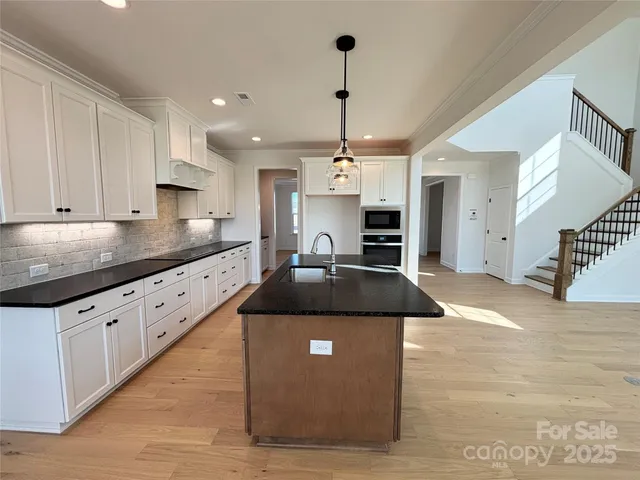 a kitchen with stainless steel appliances granite countertop a sink a stove and a refrigerator