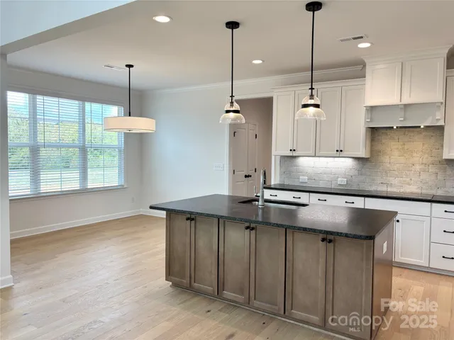 a kitchen with stainless steel appliances granite countertop a sink a window and a wooden floor