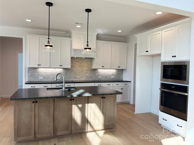 a kitchen with stainless steel appliances granite countertop a sink a stove and a refrigerator