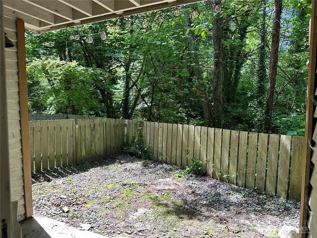 a view of a backyard with plants and wooden fence