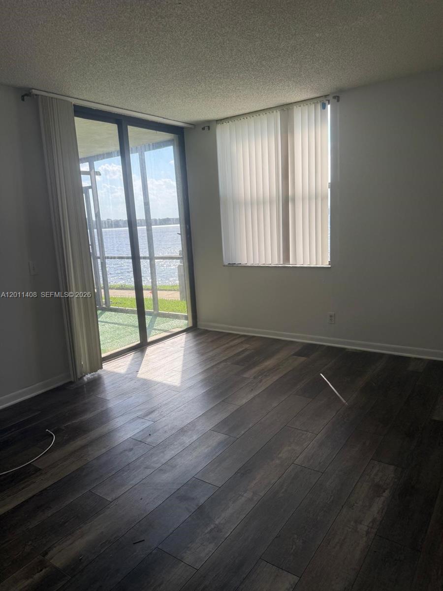 109 Lake Emerald Drive, Unit 102 Oakland Park, FL 33309 - Photo 11 of 13 an empty room with wooden floor and windows