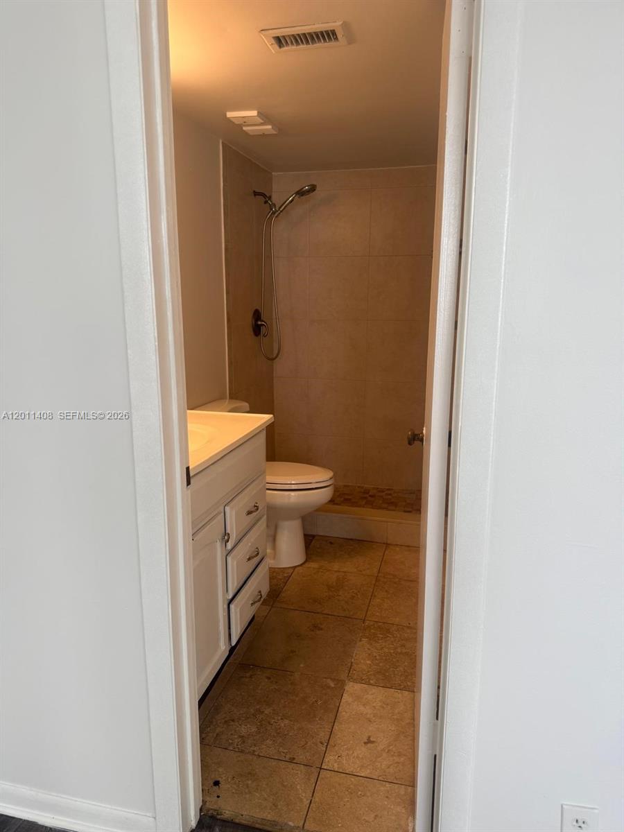 109 Lake Emerald Drive, Unit 102 Oakland Park, FL 33309 - Photo 13 of 13 a bathroom with a granite countertop toilet a sink and a mirror