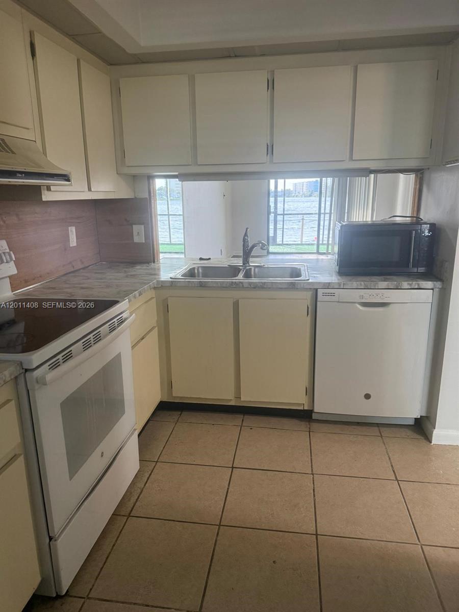 109 Lake Emerald Drive, Unit 102 Oakland Park, FL 33309 - Photo 4 of 13 a kitchen with a stove a sink and a refrigerator