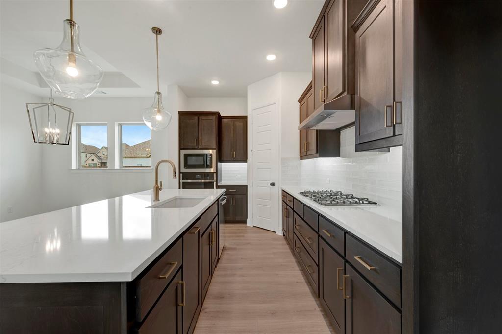 1908 Cola Drive Van Alstyne, TX 75495 - Photo 13 of 29 Spacious kitchen featuring a large central island with an undermount sink, brass faucet, and pendant lighting