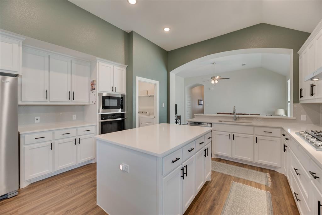 a large white kitchen with stainless steel appliances sink stove and cabinets