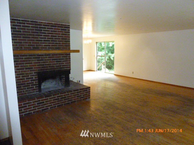 1618 194th Street Southeast Bothell, WA 98012 - Photo 5 of 20 a view of an empty room with wooden floor fire place and a window
