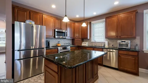 a kitchen with stainless steel appliances granite countertop a refrigerator a sink a stove a microwave and wooden cabinets