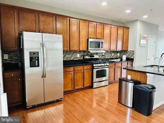 a kitchen with stainless steel appliances granite countertop a refrigerator stove and sink