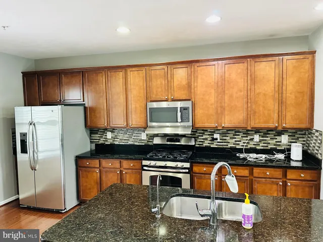 a kitchen with stainless steel appliances granite countertop a stove a sink and a refrigerator