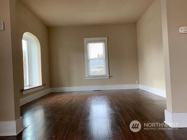 a view of an empty room with wooden floor and a window