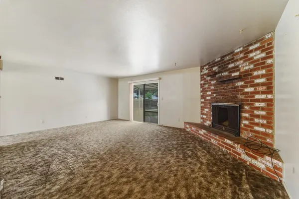 a view of an empty room with a fireplace and a window