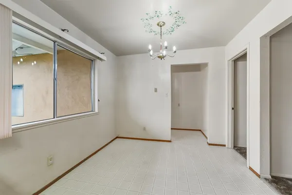an empty room with a chandelier fan and windows