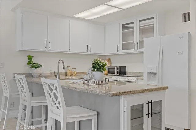 a kitchen with stainless steel appliances granite countertop a table chairs in it and white cabinets