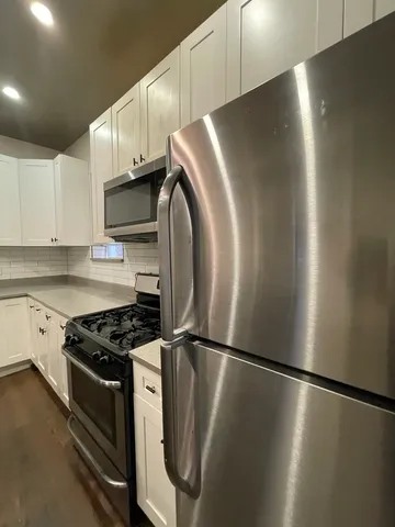 a view of a kitchen with stainless steel appliances wooden floor and cabinets