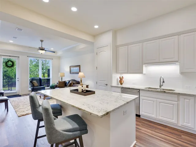 a kitchen with granite countertop a sink white cabinets and chairs