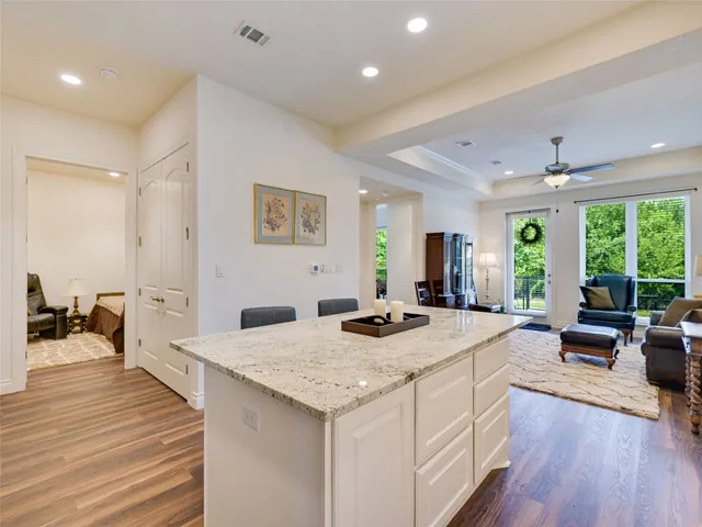 a large living room with stainless steel appliances granite countertop furniture wooden floor and a large window