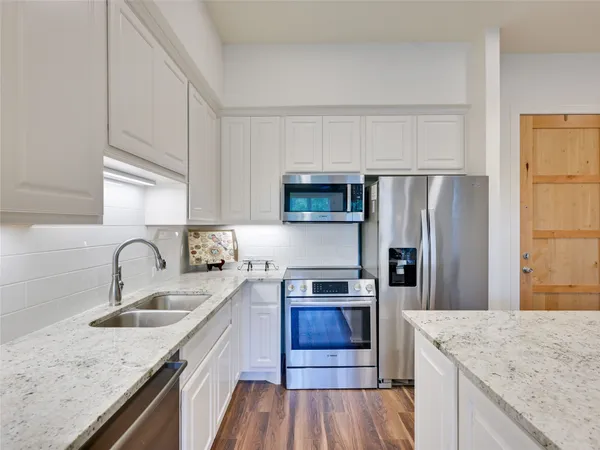 a living room with kitchen island granite countertop wooden floor and a large window
