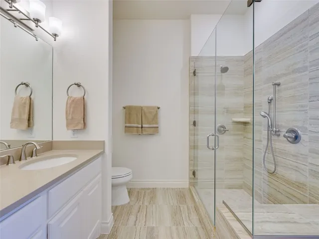 a bathroom with a granite countertop sink a toilet and shower