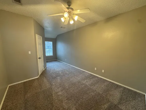 an empty room with a chandelier fan and windows