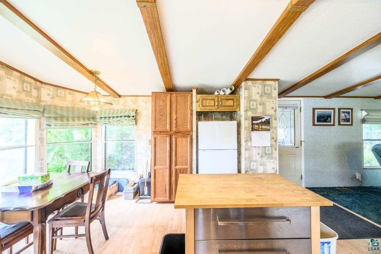 705 4th Street North Biwabik, MN 55708 - Photo 5 of 29 Dining area and kitchen space featuring wood-finish flooring, exposed ceiling beams, a built-in pantry cabinet, and a kitchen island with a wood-finish countertop