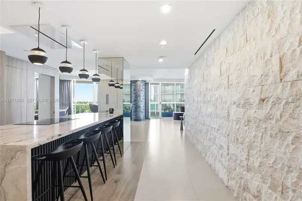 a dining hall with stainless steel appliances kitchen island granite countertop a table chairs and a refrigerator