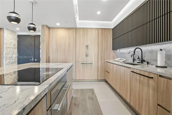 a kitchen with kitchen island granite countertop a sink a counter space appliances and cabinets