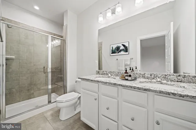 a bathroom with a toilet a sink a glass door a shower and vanity