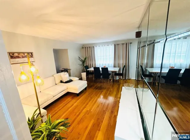 a living room with furniture a couch and dresser with wooden floor