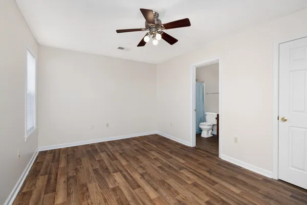 an empty room with wooden floor and a ceiling fan
