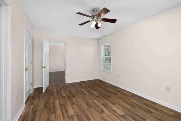 an empty room with wooden floor and a ceiling fan