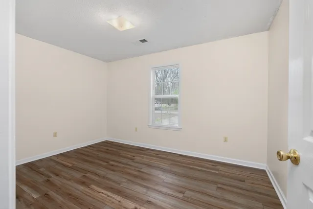 an empty room with wooden floor and window