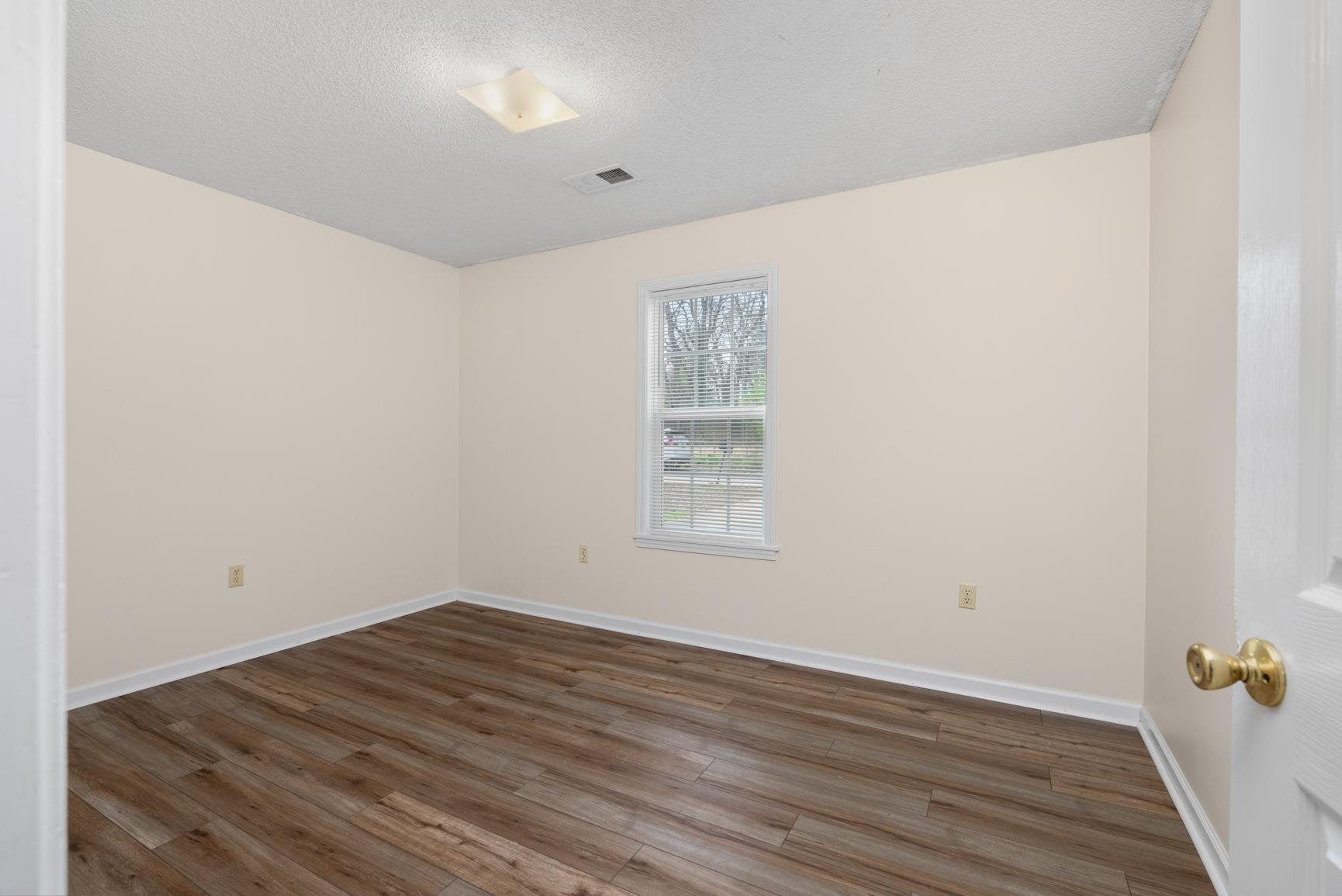 212 Feezor Street Covington, TN 38019 - Photo 27 of 31 an empty room with wooden floor and window