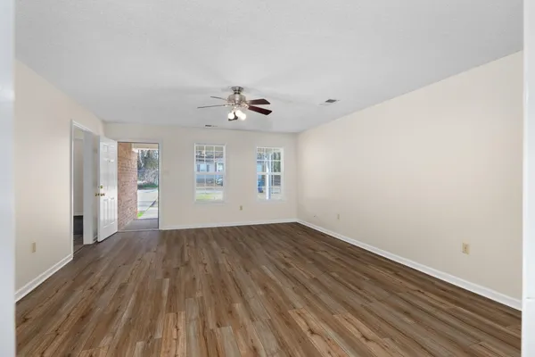 a view of an empty room with window and wooden floor