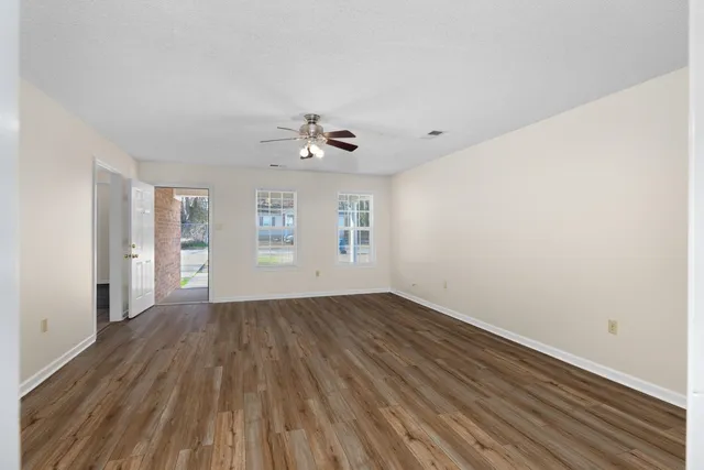 a view of an empty room with window and wooden floor