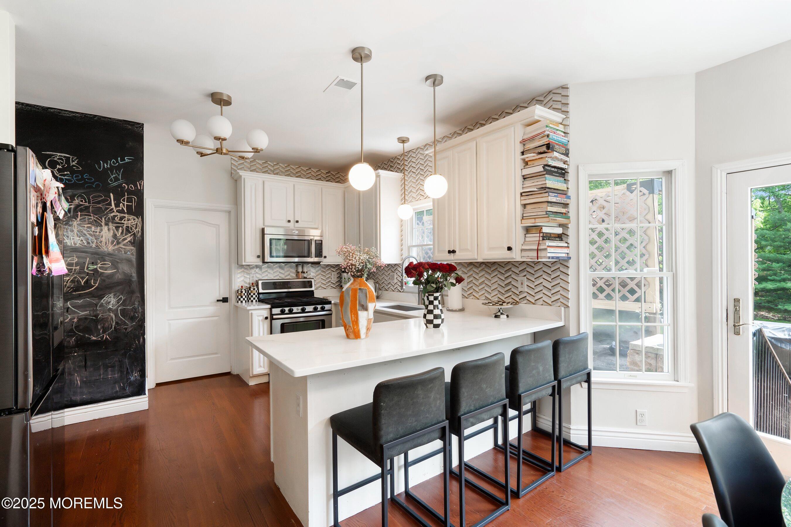 210 Rivers Glen Terrace Toms River, NJ 08755 - Photo 11 of 61 a kitchen with kitchen island a dining table chairs and a wooden floor