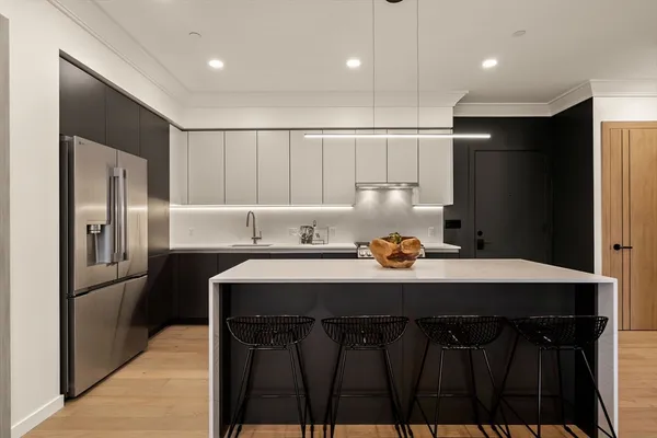 a kitchen with stainless steel appliances a sink dishwasher a refrigerator and a refrigerator with wooden floor